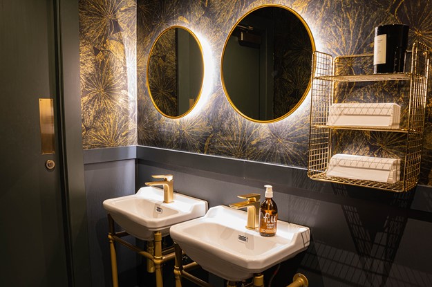 2 large gold round mirrors side by side in a bathroom with a double sink