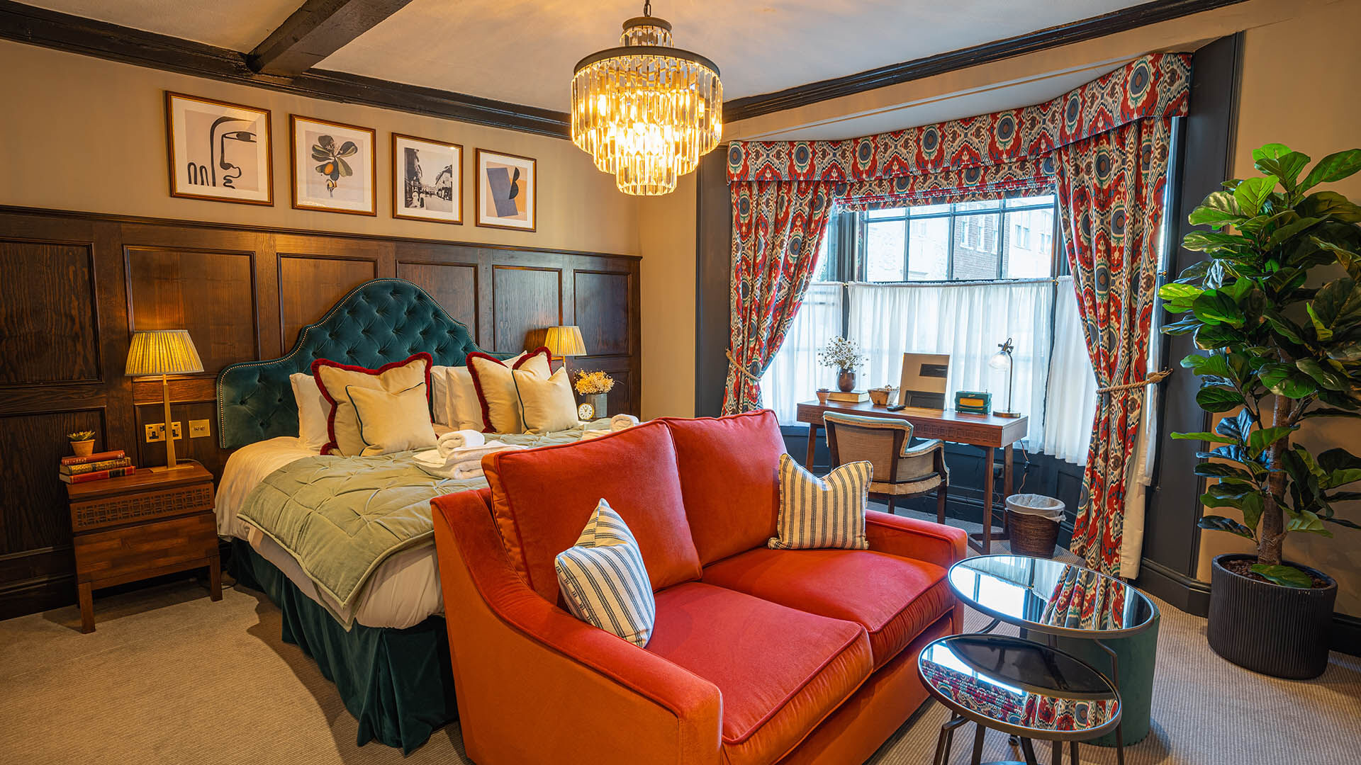 Bedroom with chandelier above the bed and red sofa at the bottom