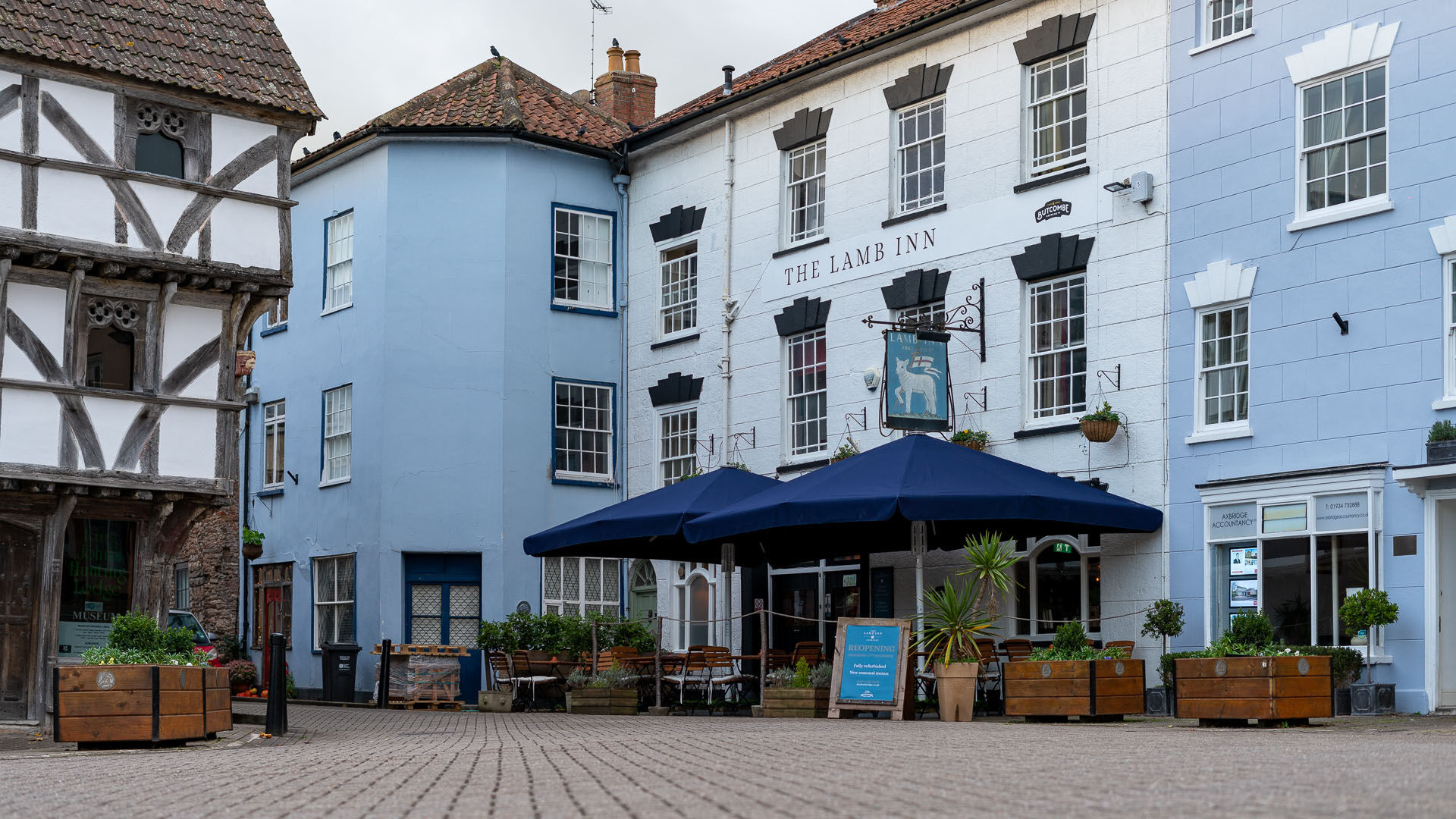 Blue pub in the centre of Axbridge with umbrellas outside 