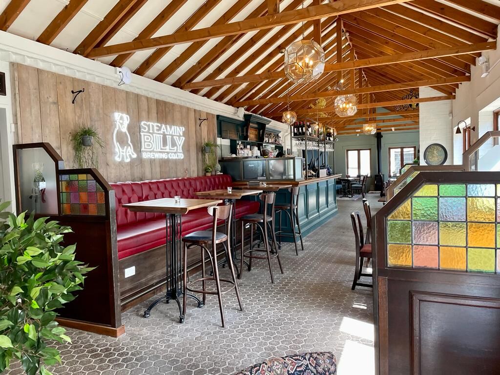 Neon sign with bar stools sin now pray later 